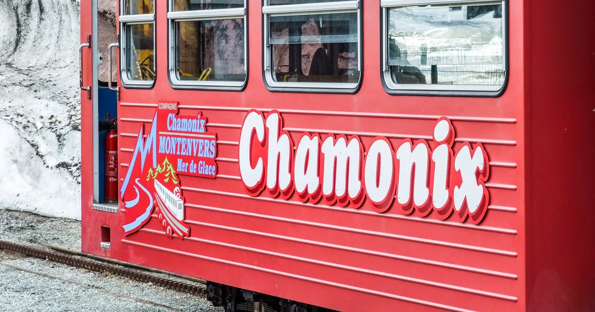 The red Montenvers rack railway train to the Mer de Glace glacier, stopped at a station with snow behind it